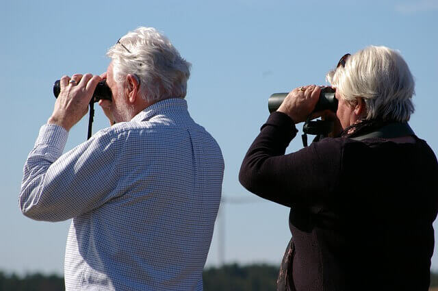 A couple with binoculars birdwatching.