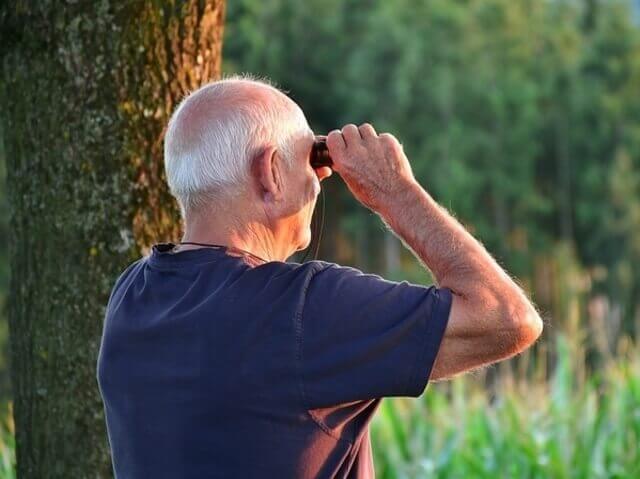 A senior with binoculars bird-watching.