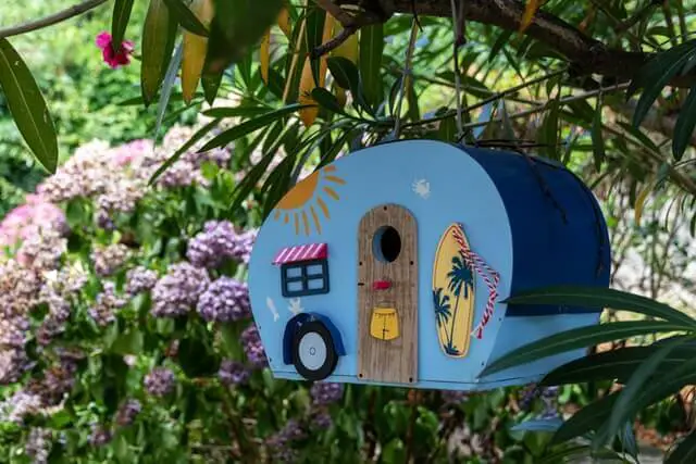 A little  blue birdhouse that looks like a trailer.