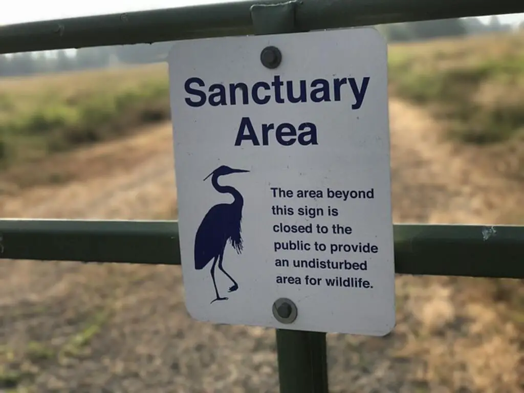 A Sign stating that the area beyond this fence is a bird sanctuary for bird conservation.