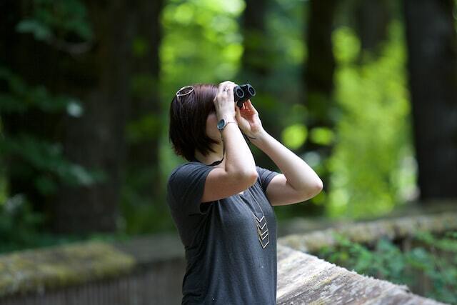 A woman watching birds with her binoculars.