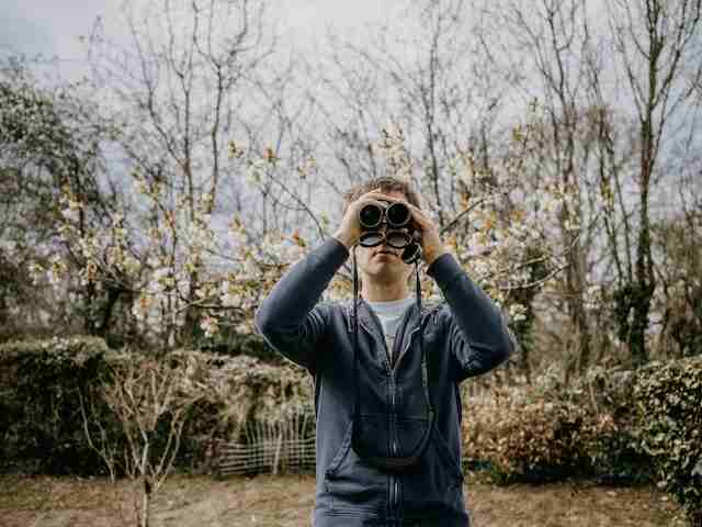 A man with binoculars birdwatching.