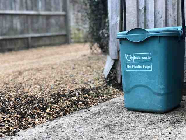 A blue compost bin in the yard.
